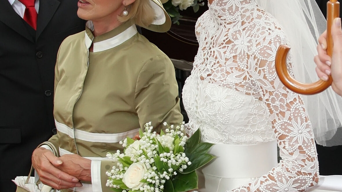 A stock image of a bride standing next to her mother with their arms linked.