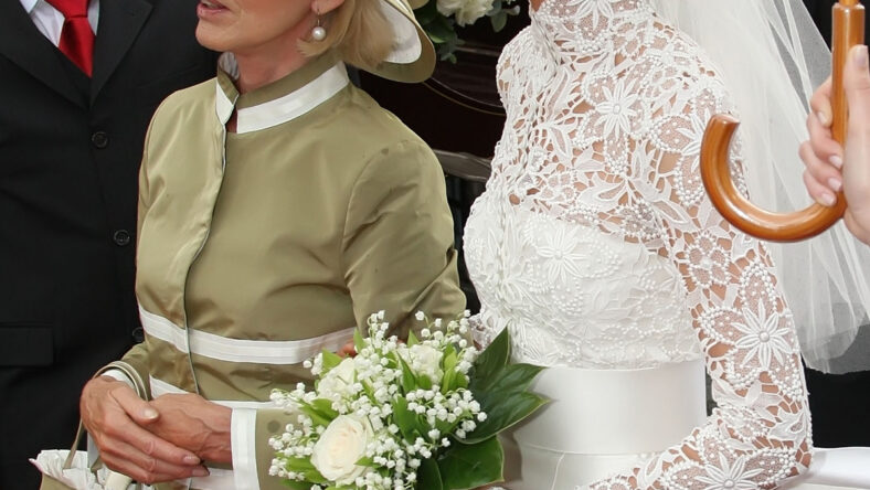 A stock image of a bride standing next to her mother with their arms linked.