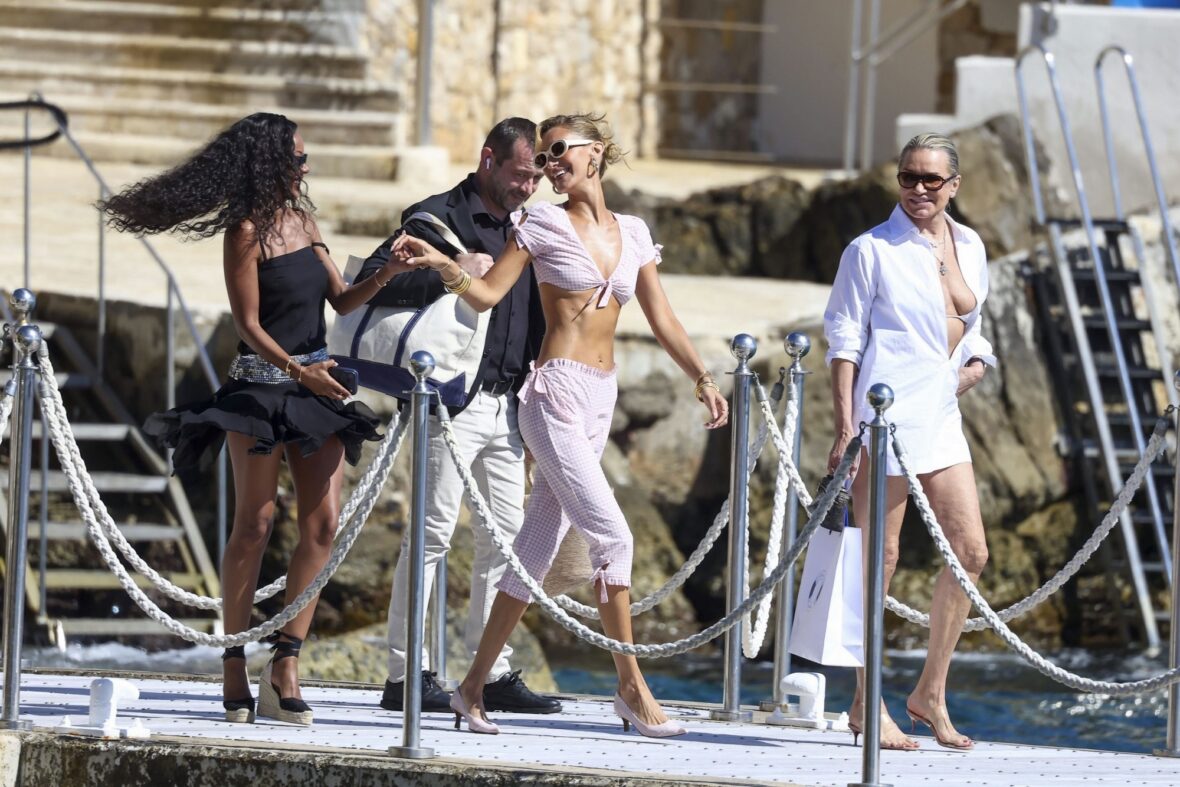 Bella Hadid wears a pink gingham outfit and sunglasses while dancing with friend on a jetty in Cannes.