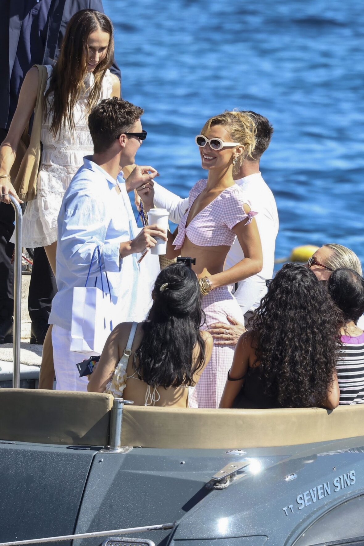 Bella Hadid wears a pink gingham outfit and sunglasses while on a boat in Cannes.