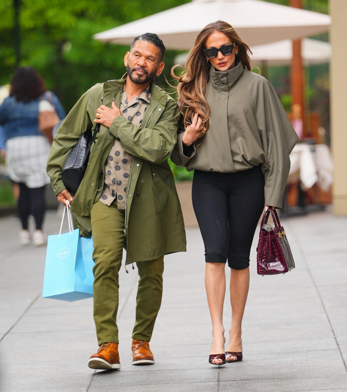 Benny Medina and Jennifer Lopez walk together in coordinated sage-green outfits