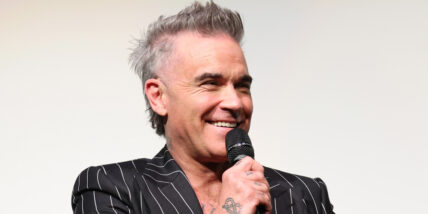 Robbie Williams holding a microphone and laughing