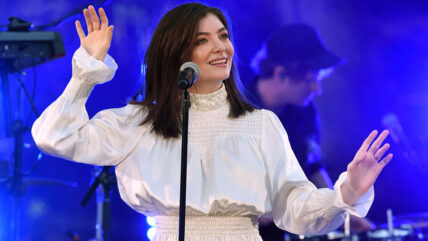 Lorde performs on stage in an all-white outfit.