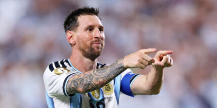 Lionel Messi pointing in his soccer uniform on the pitch