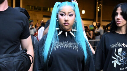 North West with blue pigtails in a spiked collar and black long-sleeve top.