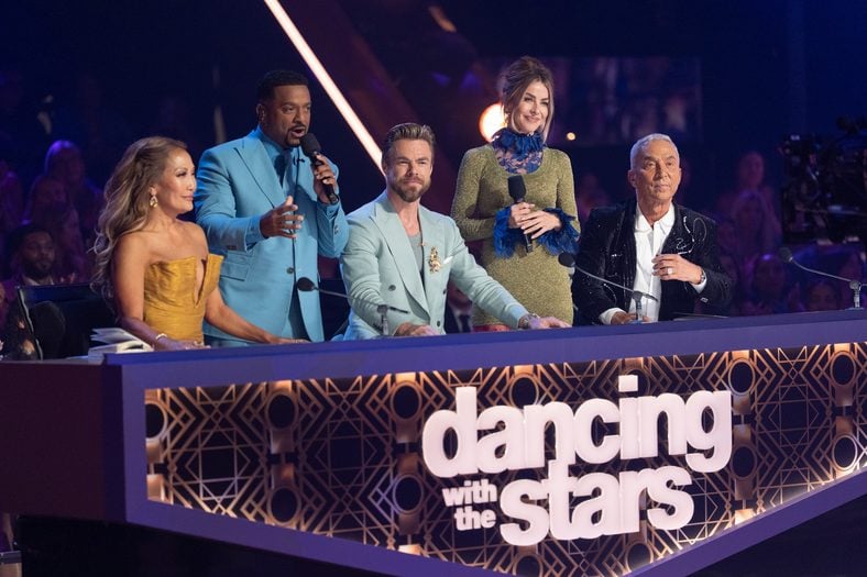 DWTS judges and hosts pose behind the judges desk 