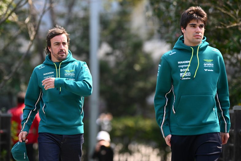 Fernando Alonso and Lance Stroll walk in the paddock at a Formula 1 race weekend