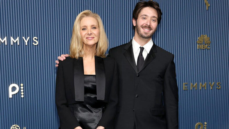 Lisa Kudrow poses with her son Julian on the 2026 Emmys red carpet. She's wearing a black satin gown with a cropped jacket and he's in a classic black suit.