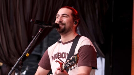 Noah Kahan performing guitar