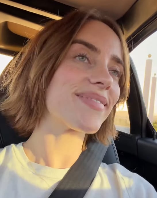 Billie Eilish smiles in a car with her shorter, layered auburn bob