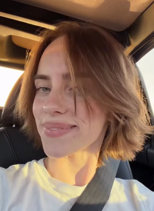 Billie Eilish turns her head to show the choppy layers of her auburn bob