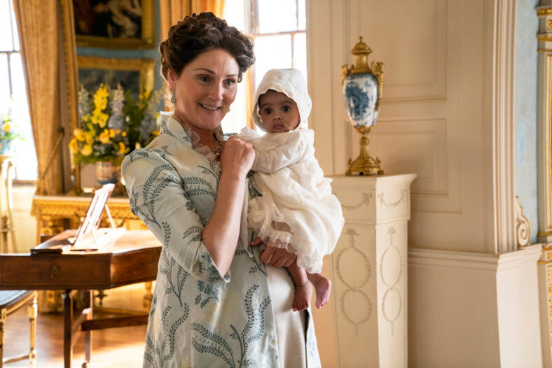 Bridgerton still featuring Ruth Gemmell holding a baby