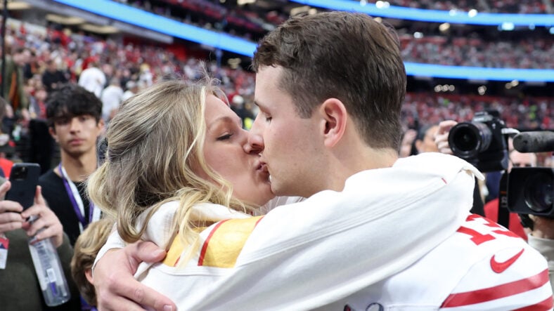 Brock Purdy kissing Jenna Purdy on the NFL field
