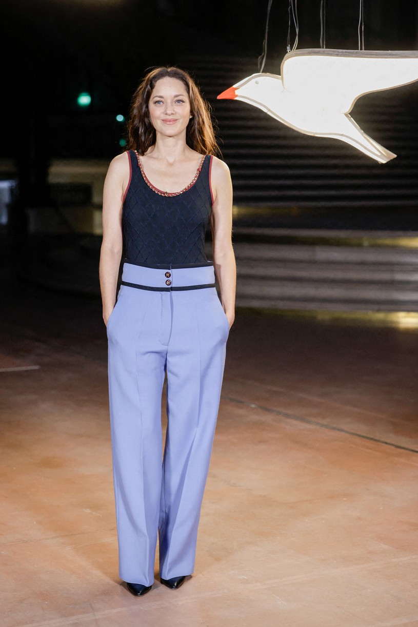 Marion Cotillard in blue pants and black top.