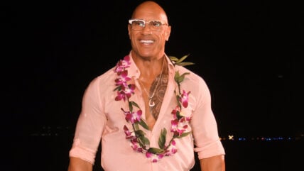 Dwayne Johnson with a lei of flowers and glasses.
