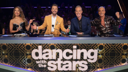 Dancing with the Stars judges pose for a photo behind the judges panel desk