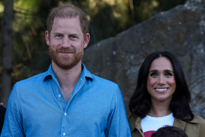 Prince Harry & Meghan Markle during a past appearance together, smiling and posing for a photo
