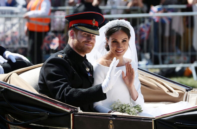 Prince Harry and Meghan Markle in their wedding attire, waving to onlookers in a carriage.