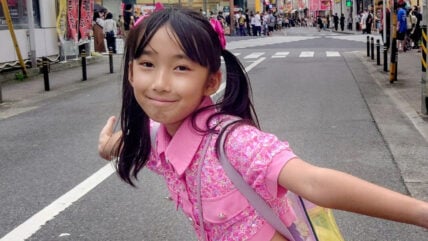 Hirata Runa posing for a photo with her arms outstretched in a street