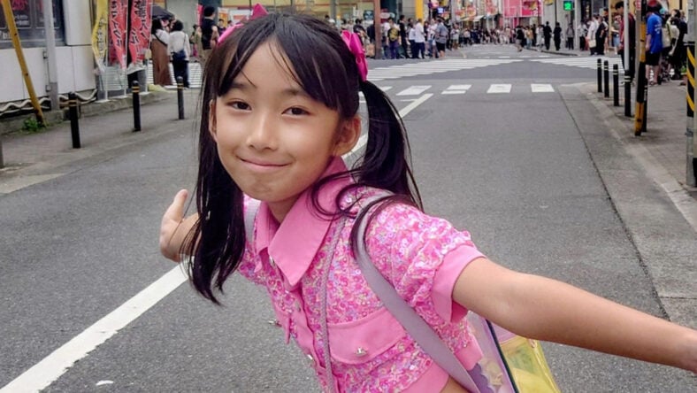 Hirata Runa posing for a photo with her arms outstretched in a street