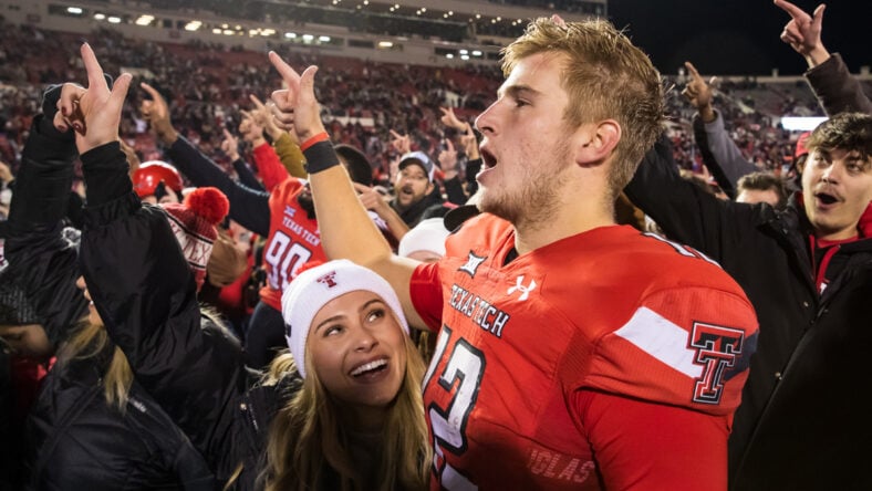 Quarterback Tyler Shough #12 of the Texas Tech Red Raiders stands on the field with his fiancée Jordan Wormdahl after the win against the Oklahoma Sooners at Jones AT&T Stadium on November 26, 2022 in Lubbock, Texas.
